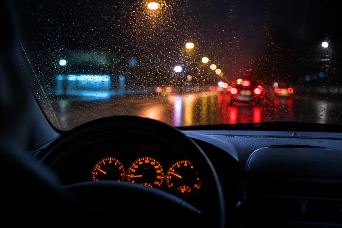 Tableau de bord de voiture avec le témoin moteur orange allumé, vue rapprochée de nuit